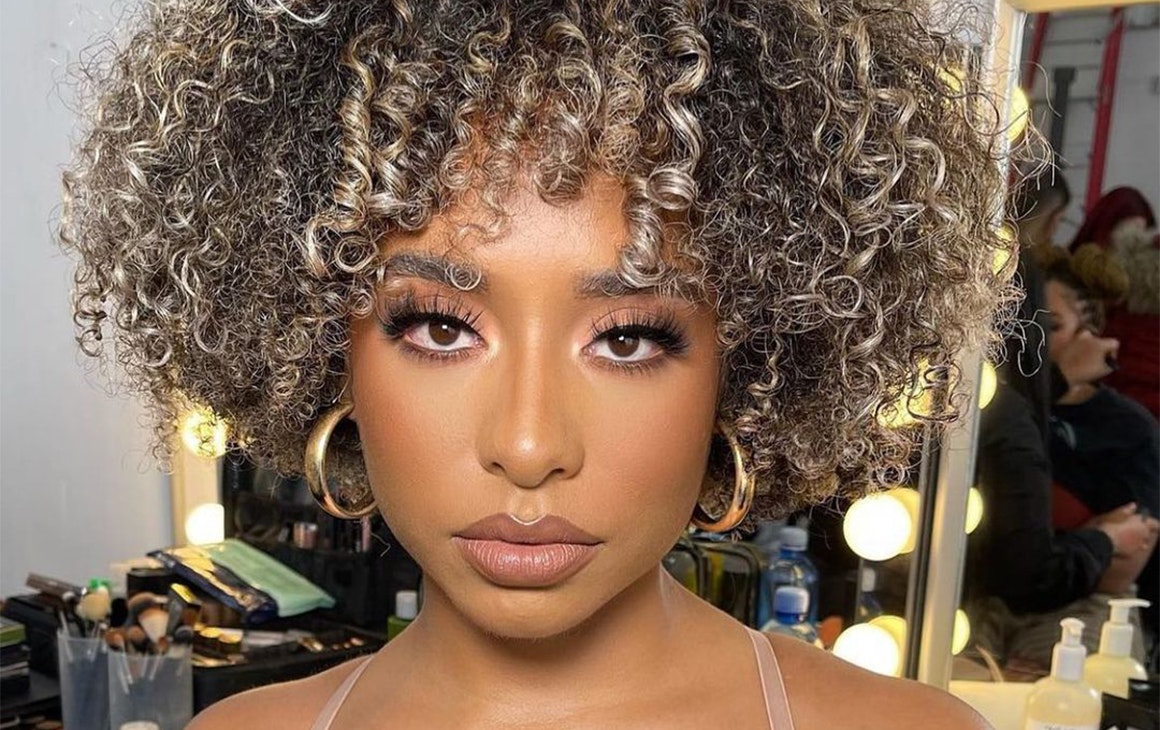a woman with a curly fro with highlighs